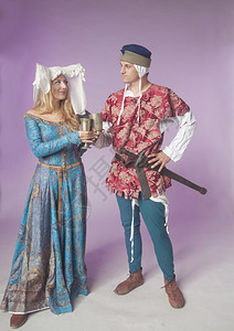 演播室拍摄的一对年轻夫妇穿着中世纪服装在紫色图片