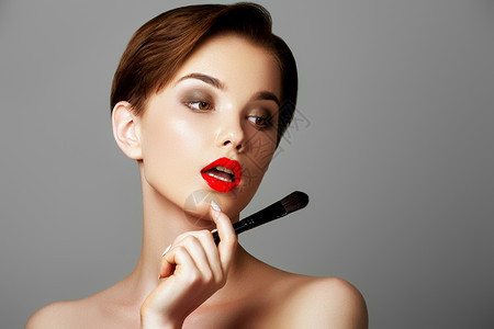 化妆师涂上红色唇膏美丽的女人脸化妆师之手图片