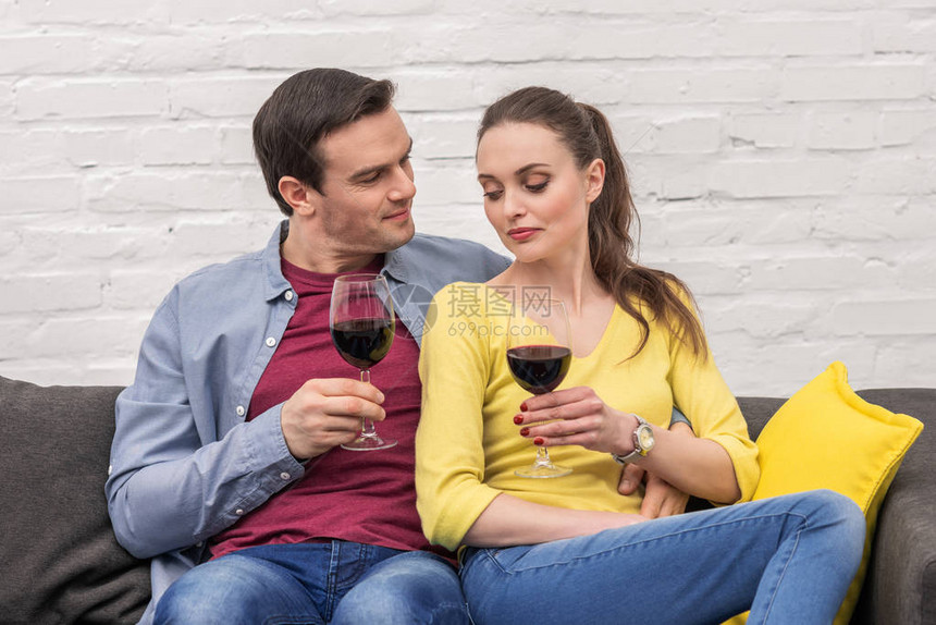 带着红葡萄酒杯的美成人夫妇在家共度时图片