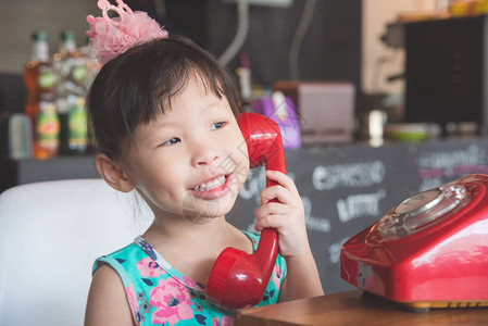 小亚洲女孩在用红经典电话与朋友交图片
