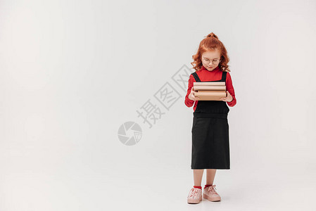 美丽的小女学生携带大量书本在图片