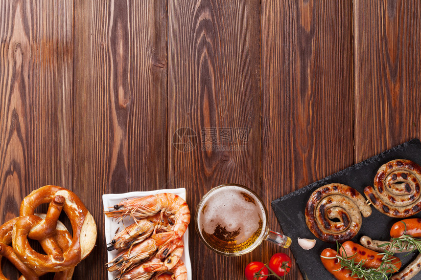 啤酒杯烤虾香肠和脆饼放在木制桌上顶视角图片