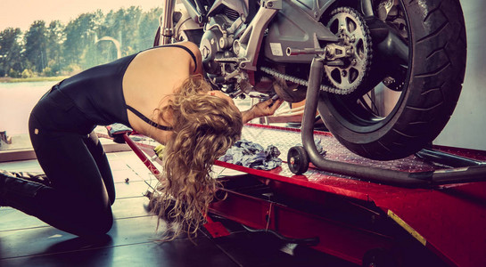 在车库里修理摩托车的金发女郎图片