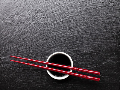 黑石背景的酱油碗上的日本寿司筷子带有复制空图片