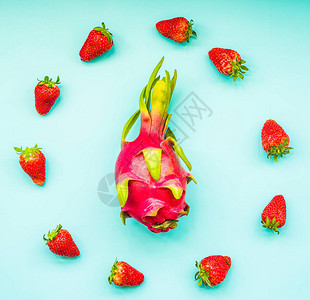 新鲜的有机火龙果草莓蓝色背景顶视图图片