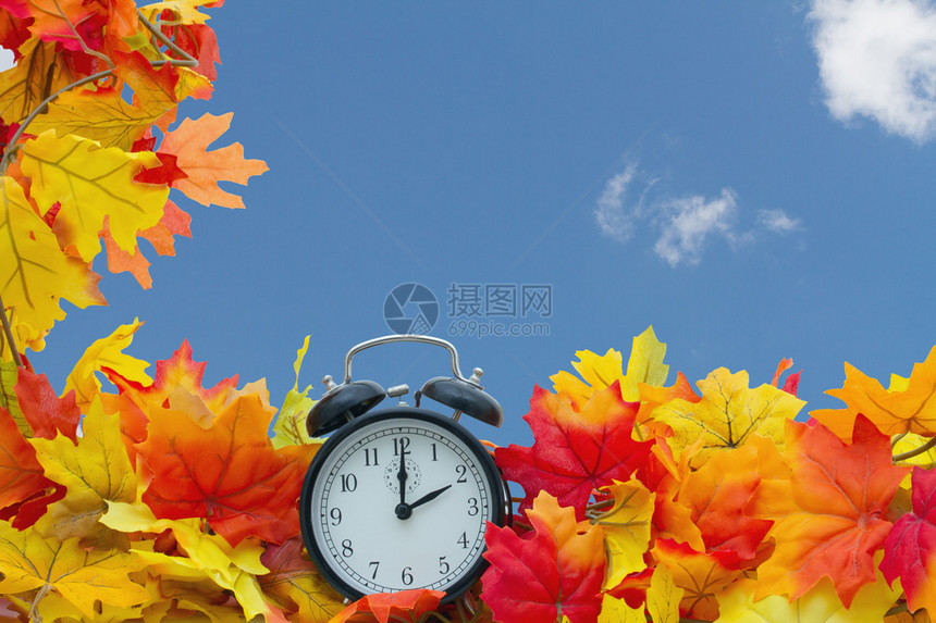 秋叶背景秋叶和带有天空背景的闹钟图片