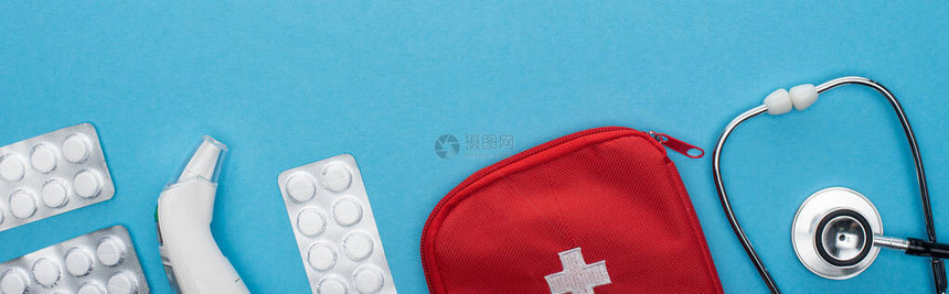 泡袋听诊器急救包和蓝底耳温度计中的药片顶部视图片