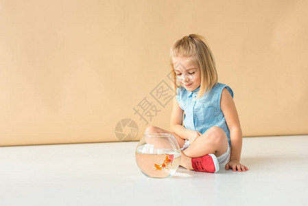 可爱的孩子盘腿坐着看着鱼缸图片