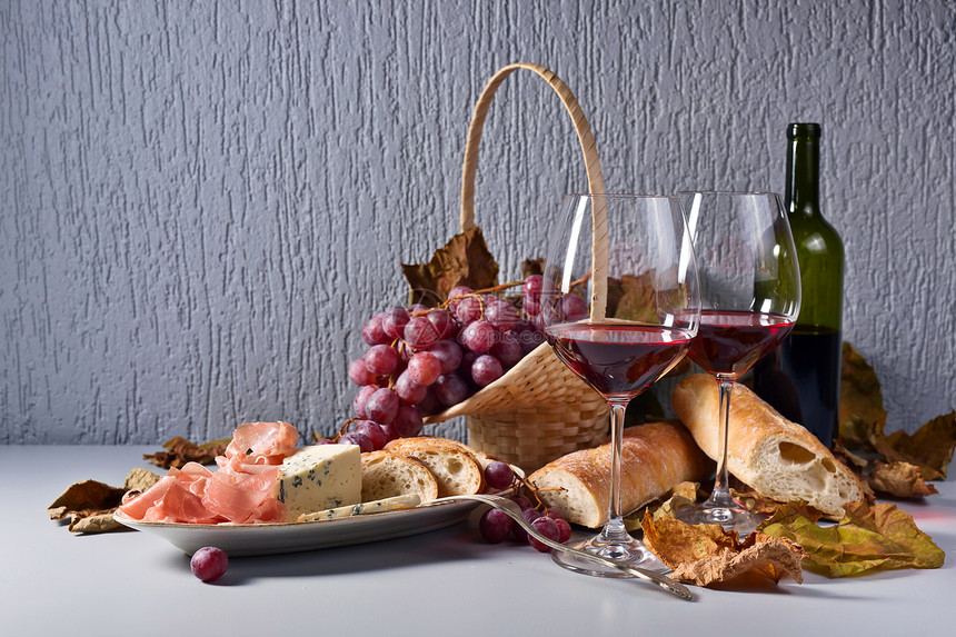 红酒加零食和葡萄蓝奶酪香肠和餐桌上的面图片