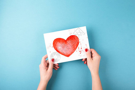 女手持彩色心胸印在蓝底的卡片最微小的风格构成情人节贺卡图片
