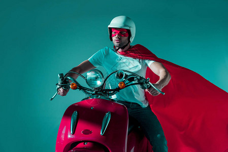 戴防护头盔超级英雄面具和骑红色摩托车的图片