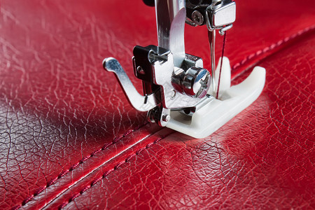 缝纫机和带有接缝特写的红色皮革图片