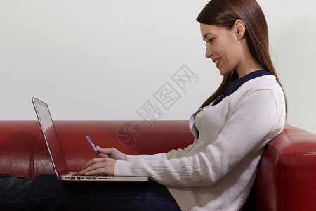 在家网上购物时使用Pc和信用卡与快乐妇女进行电子商务SideView图片
