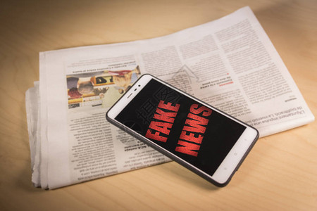 报纸上的屏幕上写着红色假新闻的智能手机图片