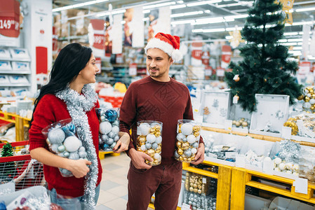 一对年轻夫妇在店铺家庭传统上装满了圣诞球的箱子图片