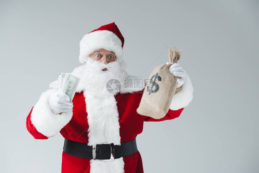 惊讶的圣诞老人拿着美元钞票和被白图片