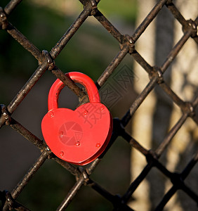 红色的心形锁挂在公园的栅栏上是永恒的爱背景图片