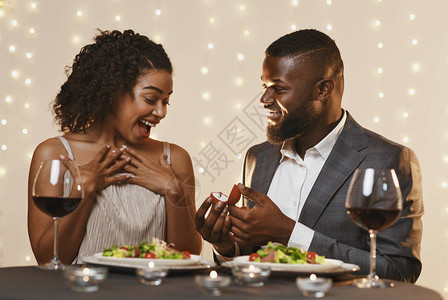 情人节求婚黑人男子在餐厅吃饭时向他惊讶的美丽女人求婚图片