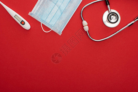 红色背景带温度计和听诊器的医疗图片