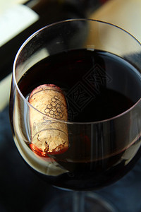 一杯红酒背景是软木塞和瓶子图片