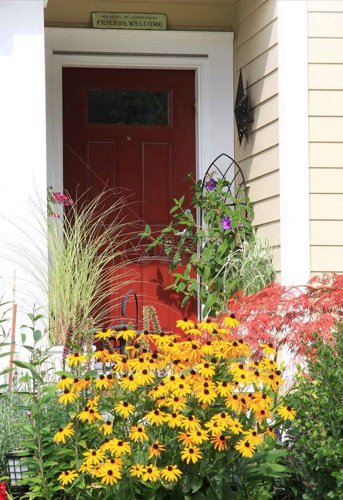 鲜艳的红色前门被五颜六色的鲜花包围图片