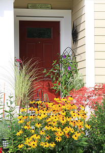 鲜艳的红色前门被五颜六色的鲜花包围图片