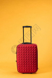 黄色背景带轮子的红色旅行包图片