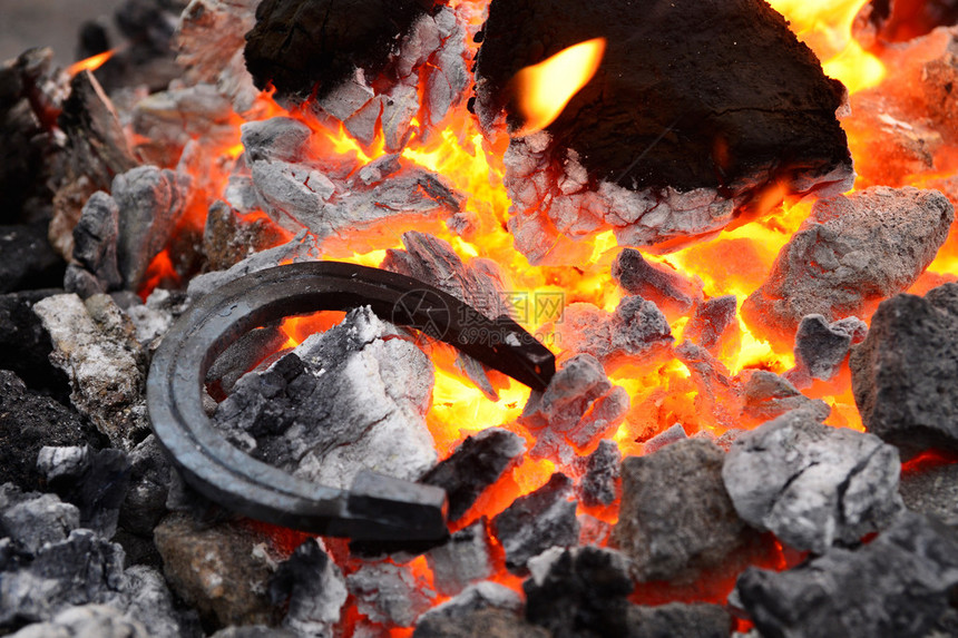铁马蹄铁躺在热煤和燃烧的火焰上图片