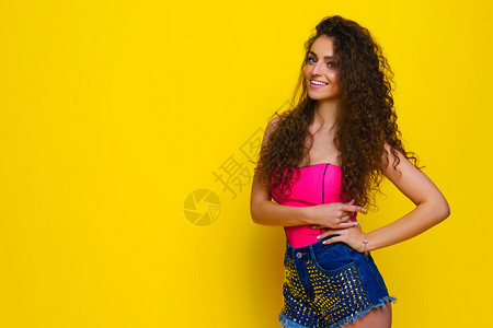 身穿粉红色衬衫和黄色背景蓝短裤的年轻美图片