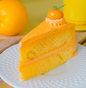木桌上白盘子里的橙子蛋糕图片