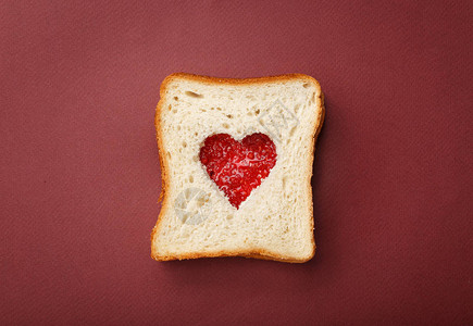 两片面包堆在一个三明治里面切开满了草莓果酱的心图片