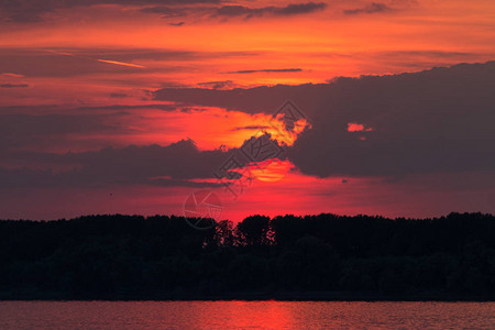 垂死的太阳在日落背景的深红色多云天空图片