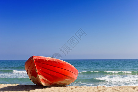 靠近大海的滩上的红船背景图片