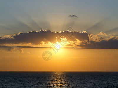 夕阳的光芒冲破海上的云层图片