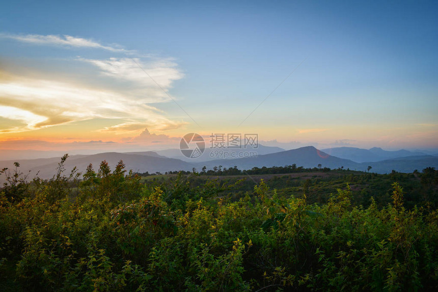 山丘上黄色和蓝色的天空与山地风景的田野日落美景背图片