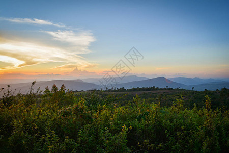 山丘上黄色和蓝色的天空与山地风景的田野日落美景背图片