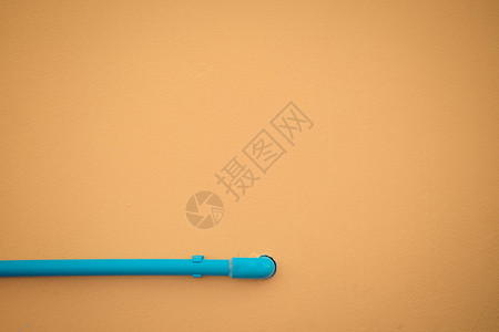 最小化风格黄墙纹理背景上的蓝色水管古背景图片