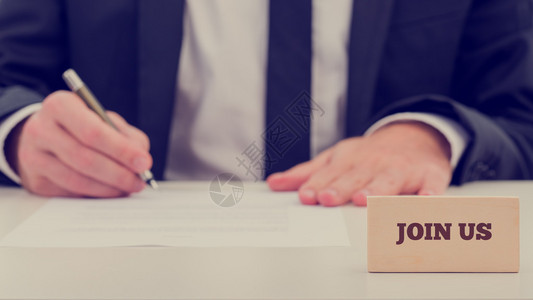 一个商人坐在完成一份工作申请或登记表上图片