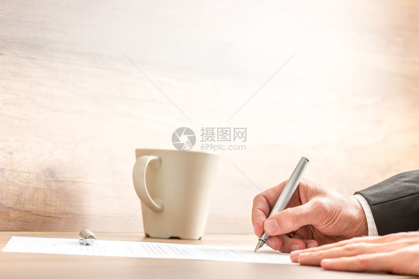 一个商人的手在一张纸上用银笔写字图片