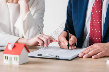商业女商人在贷款协议签字地靠近持有笔的客户附近指着签名背景图片