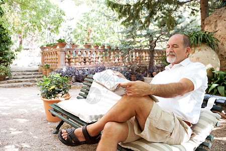 老人在豪华度假别墅绿色花园中放松图片