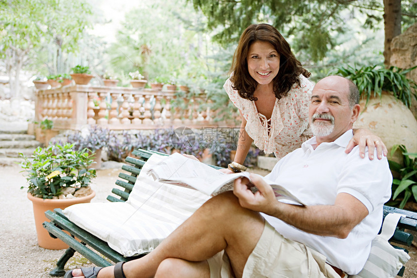 在豪华酒店的花园里与男人阅读报纸享受假期图片