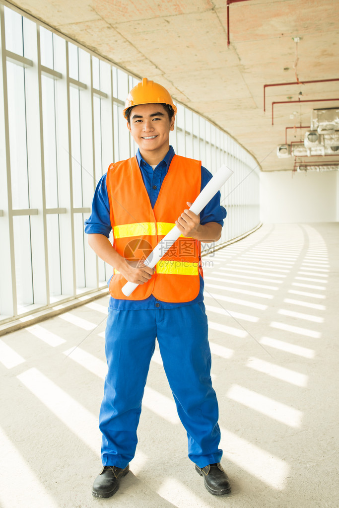 一位年轻建筑师的完整肖像他拿着蓝图站立图片