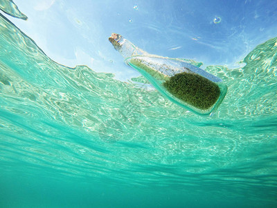 漂浮在海中的瓶子里的消息有沙子的玻璃瓶和水图片