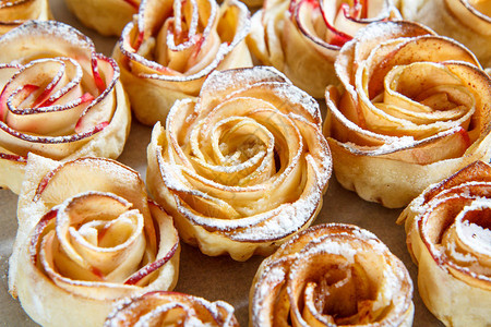 烘烤纸上玫瑰形式的苹果自制饼干关闭顶端视图食物背景Fo图片