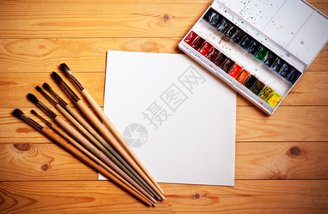 水彩颜料油漆刷子和木制背景的纸图片