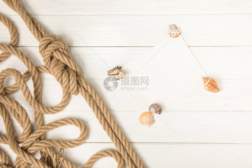 白色木质表面带贝壳的棕色航海结绳和图片
