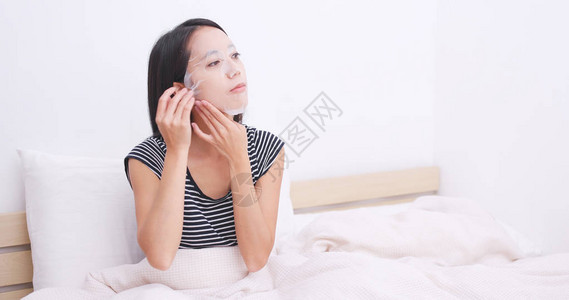女人躺在床上把纸面膜敷在脸上图片