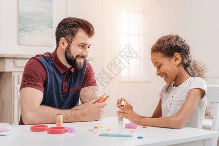 多民族快乐的父亲和女儿在家里一起画钉子图片