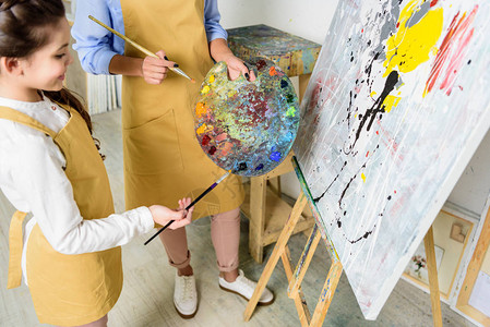 艺术学校车间在调色板上选择油漆的教师和学图片
